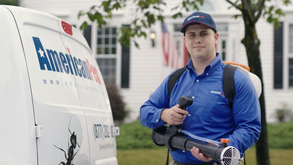 An American Pest technician reviewing the yard with a homeowner by a garden fence