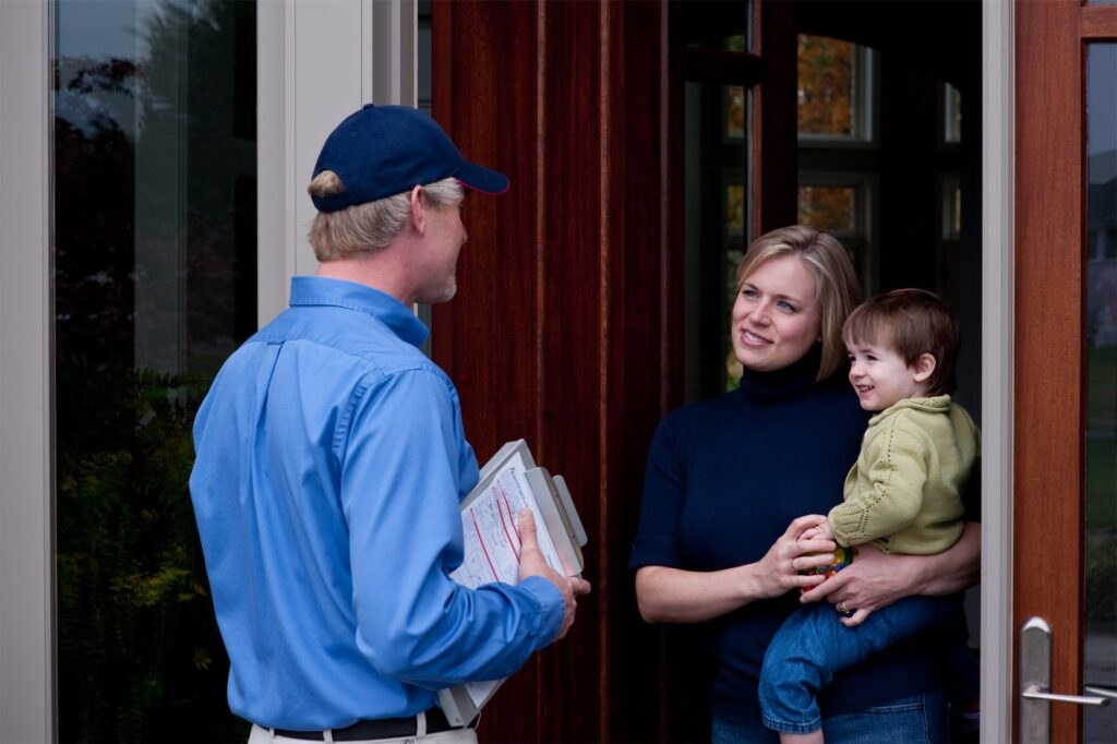 An American Pest technician greeting a family at their front door